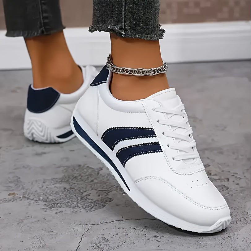 White low-top sneakers with navy side stripes and lace-up fronts