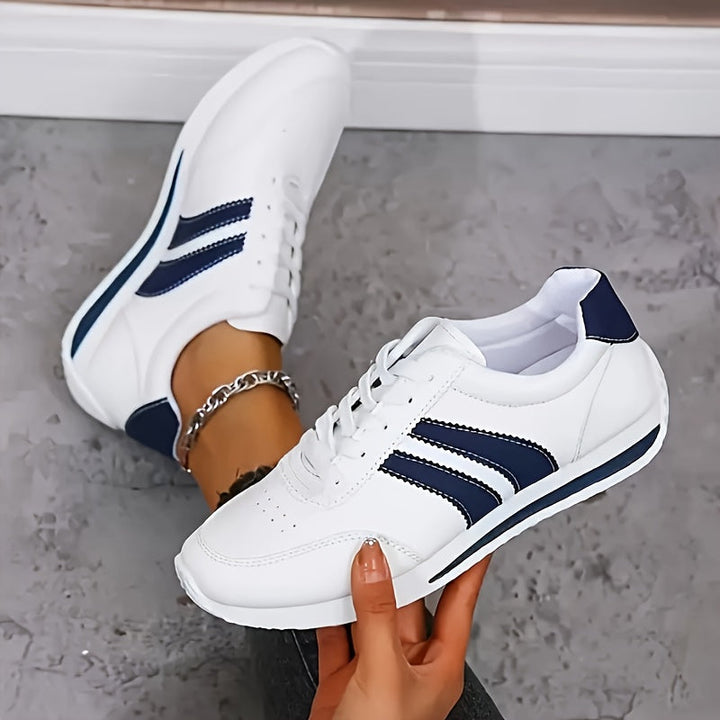 White low-top sneakers with navy side stripes and lace-up fronts