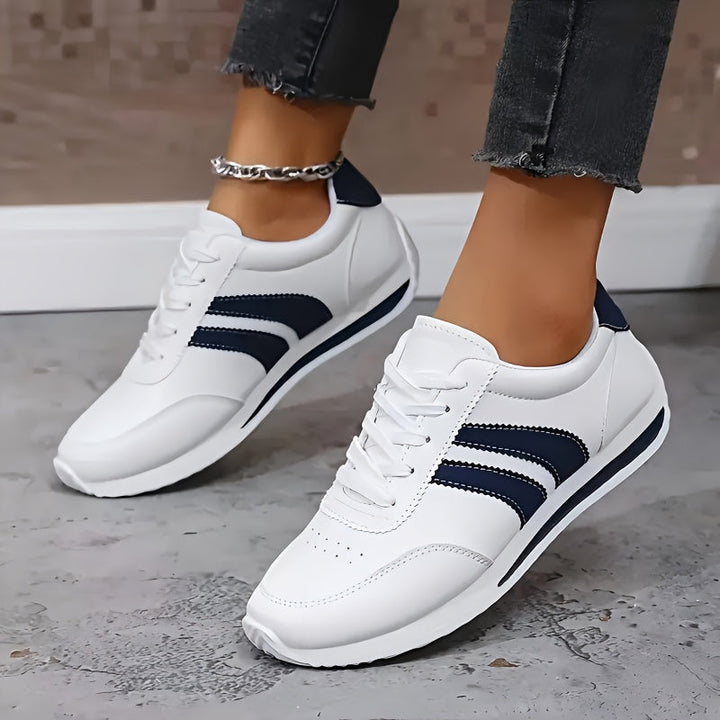 White low-top sneakers with navy side stripes and lace-up fronts