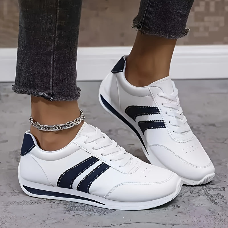 White low-top sneakers with navy side stripes and lace-up fronts