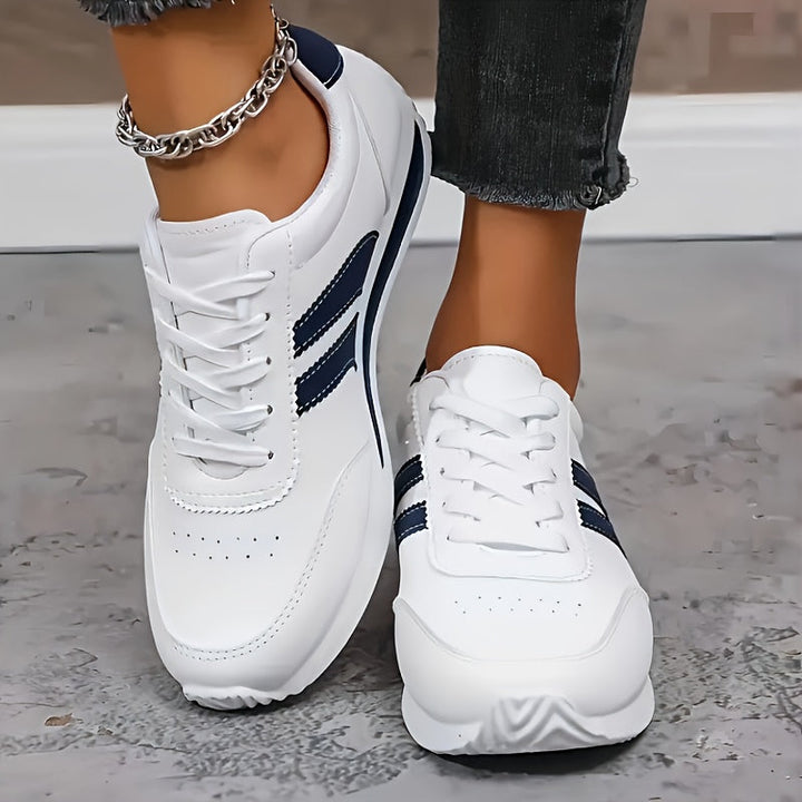 White low-top sneakers with navy side stripes and lace-up fronts