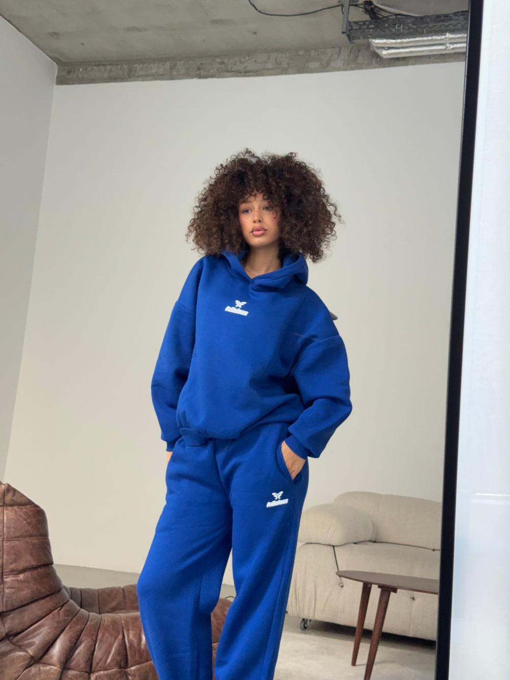 Women's blue pullover hoodie with white chest logo and hood