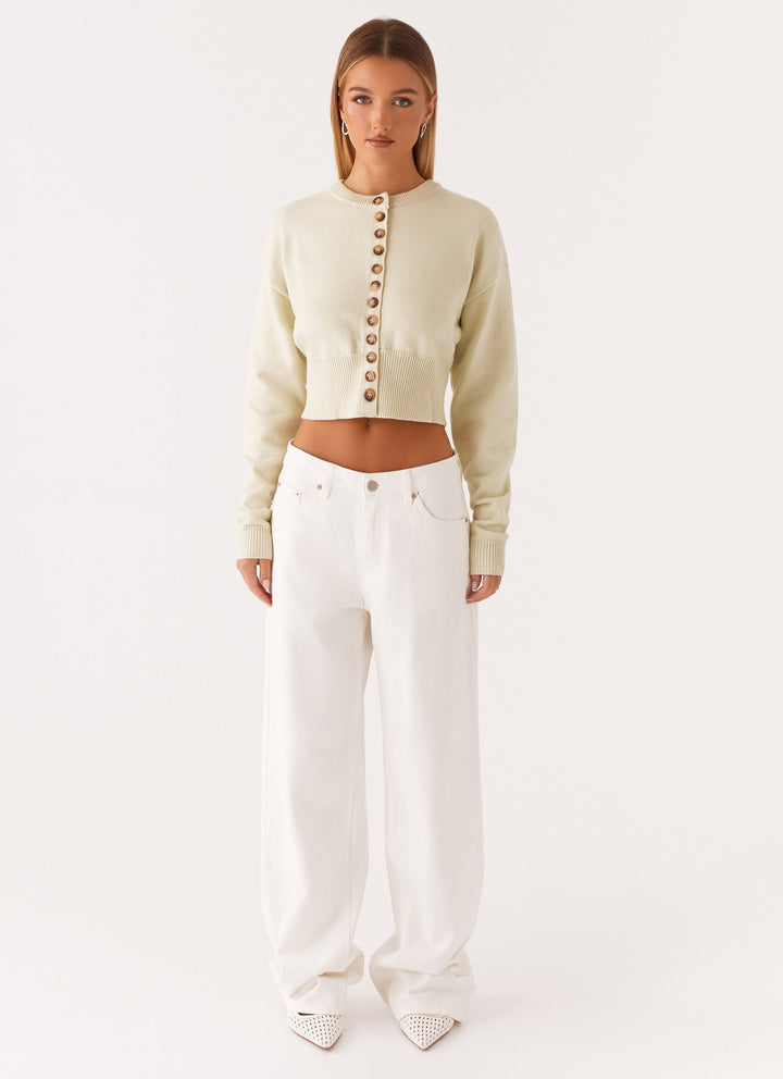 Women's cream cropped knit cardigan with brown buttons and long sleeves