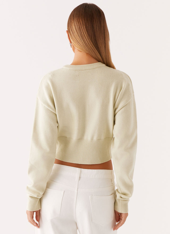 Women's cream cropped knit cardigan with brown buttons and long sleeves